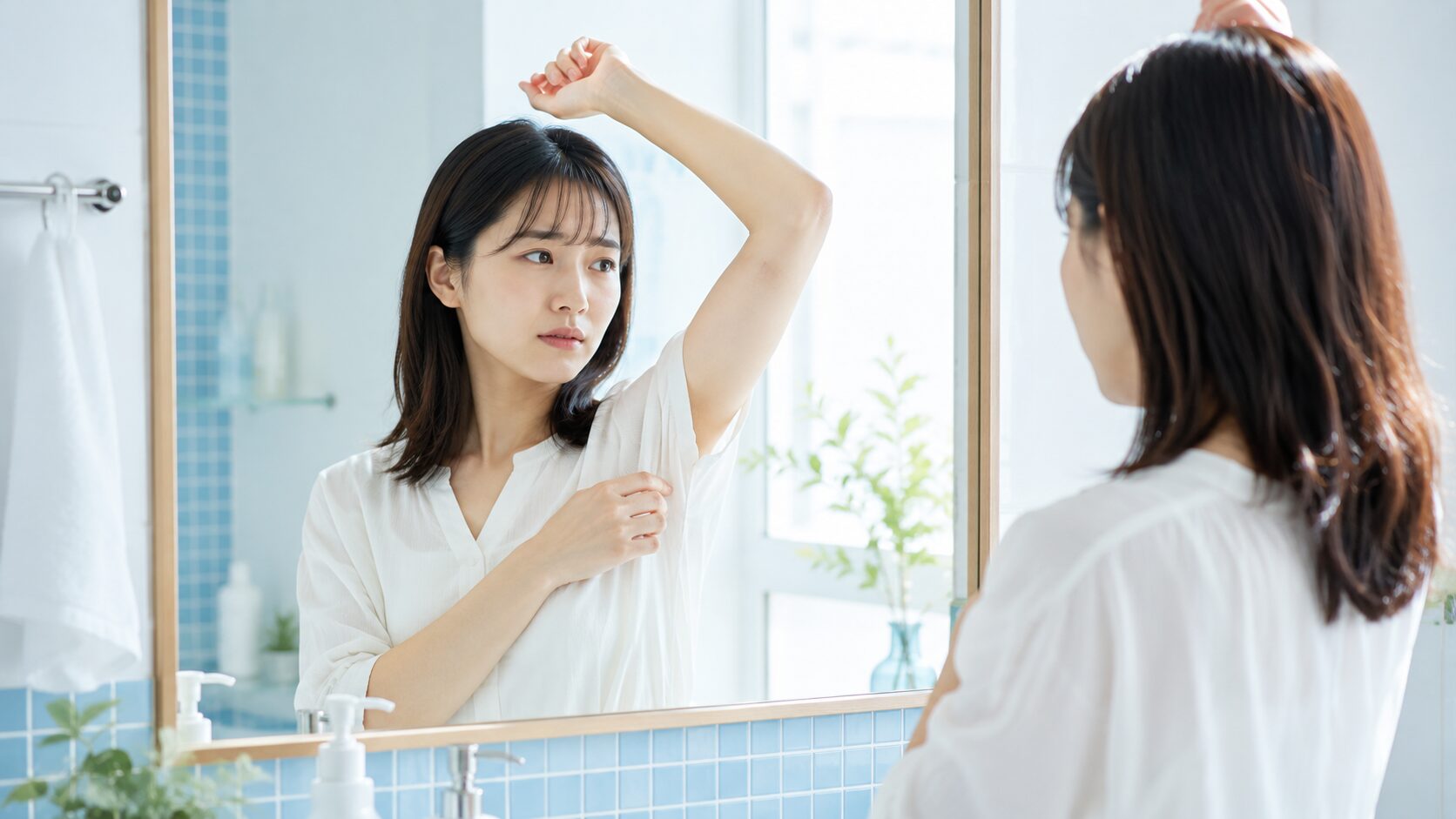 鏡の前でワキガのセルフチェックをする女性｜朝のバスルームで脇のにおいを確認するシーン