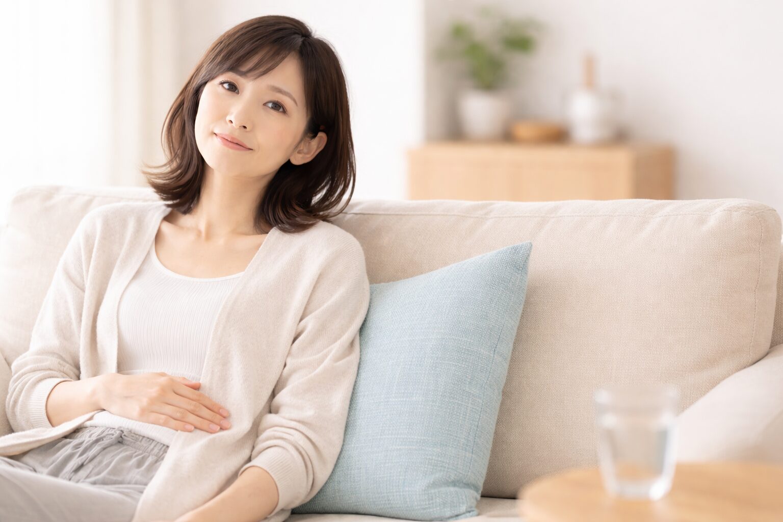 お腹の不調を感じながら口臭を気にする女性｜内臓由来の口臭イメージ