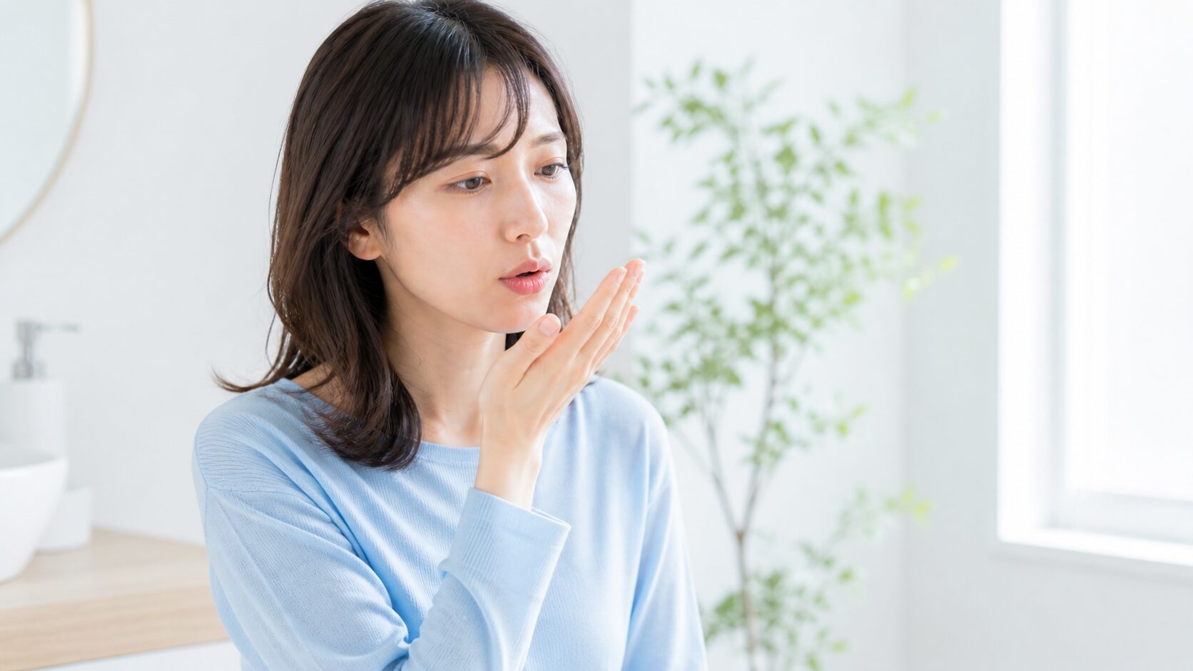 手のひらに息を吐いて口臭をセルフチェックする女性｜気になり始めたサインに早めに気づく