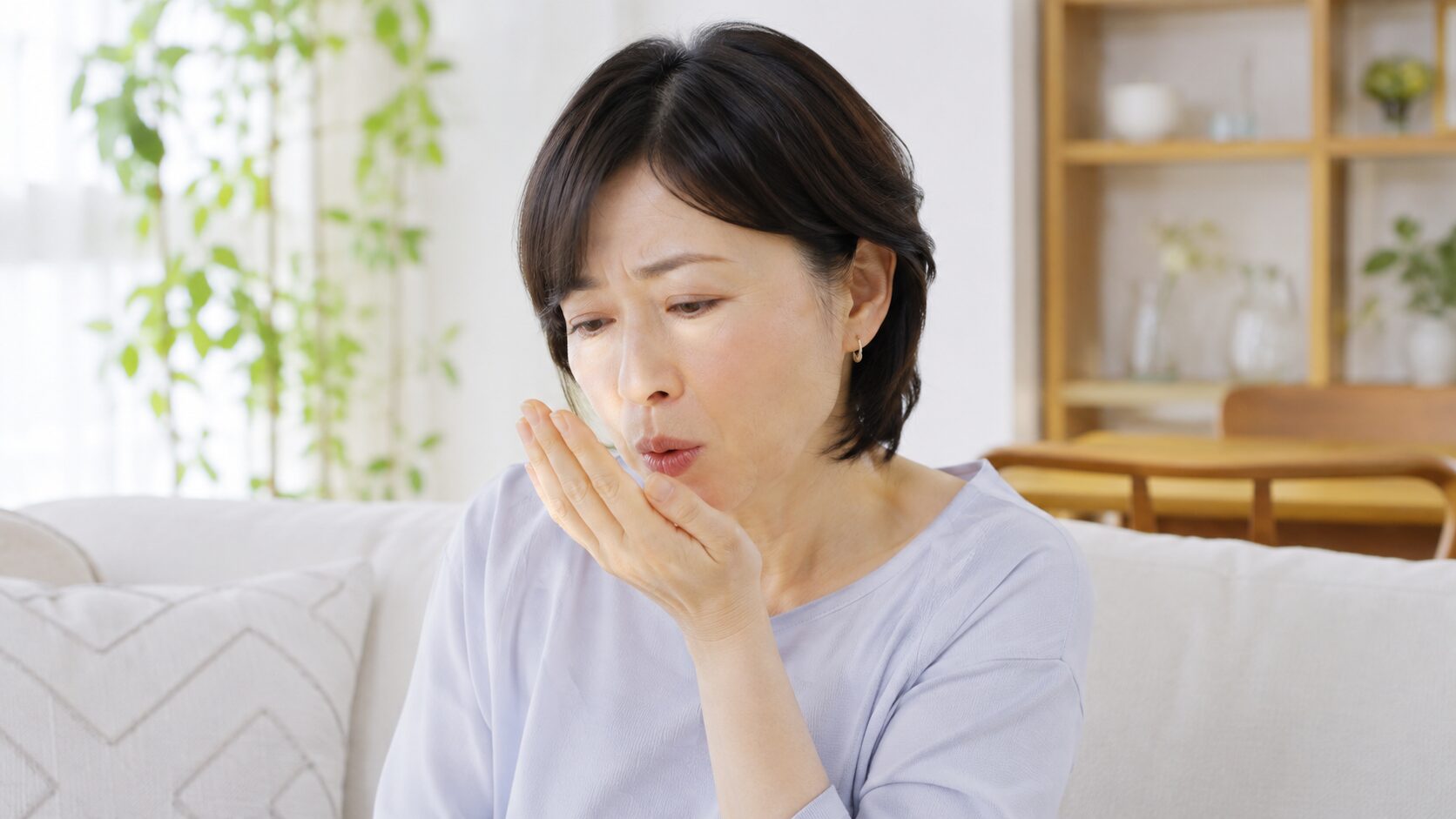 手に息を吐いて口臭を確かめる女性｜加齢口臭のセルフチェック