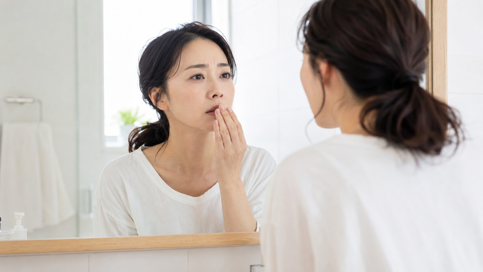 歯周病と口臭のセルフチェック｜鏡の前で口元を確認し息のニオイを気にする女性