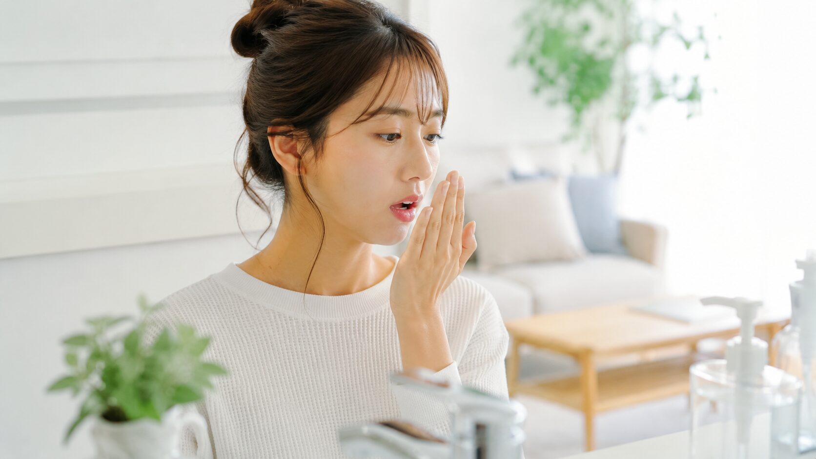手のひらに息を吐いて口臭をセルフチェックする女性｜気になり始めたサインに早めに気づく